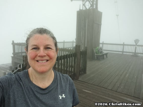 photo of woman standing on a wood platform with radio tower in background