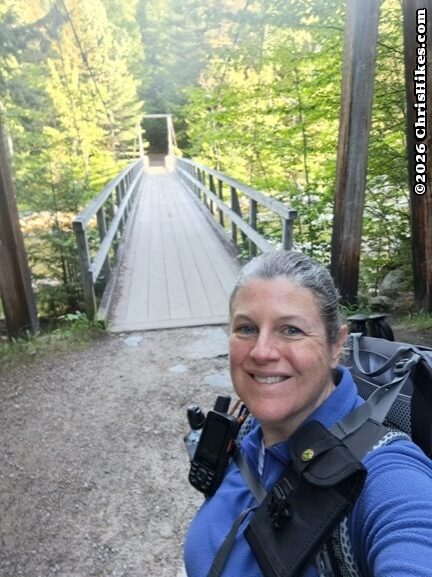 Photo of woman in front of suspension bridge