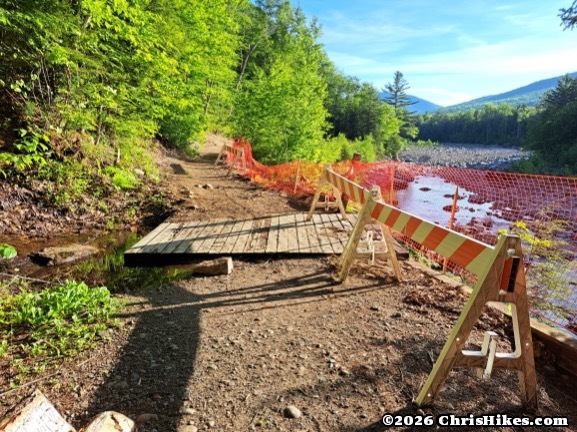 photograph of hiking trail with construction barriers and river on the right side