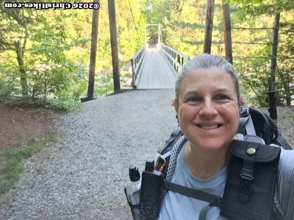 woman standing in front of a suspension bridge