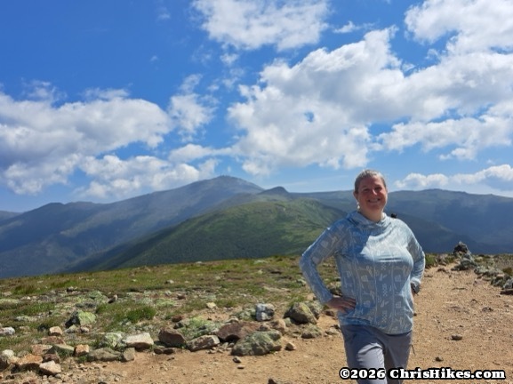 Woman standing with hands on hips, blue-green rolling mountains in background