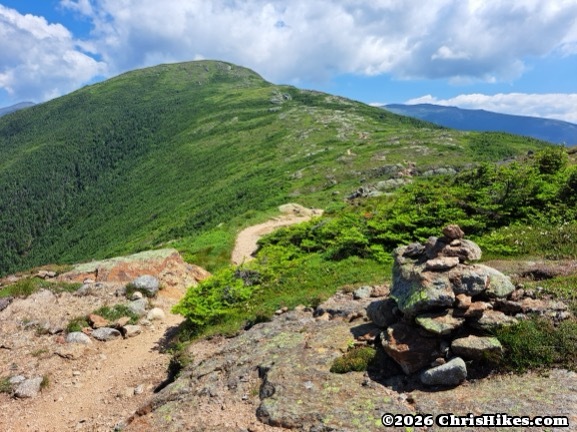 Tan trail stretching through green rolling mountain tops