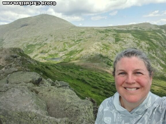Selfie of woman with grey rocky mountains in background