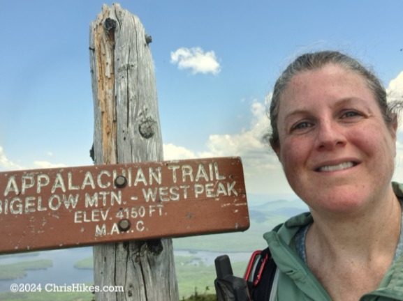 Chris standing next to West Peak summit sign