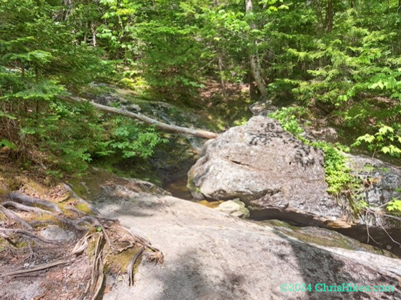 Photograph of small stream flowing in between boulders