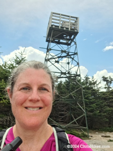 Photograph of woman with fire tower in background