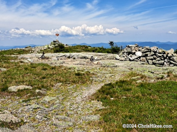 Photograph of mountain summit with sign and rock shelter