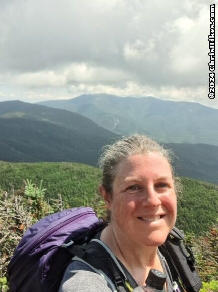 photograph of woman with mountains and clouds in background