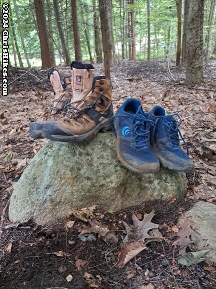 photograph of hiking boots and sneakers on a rock